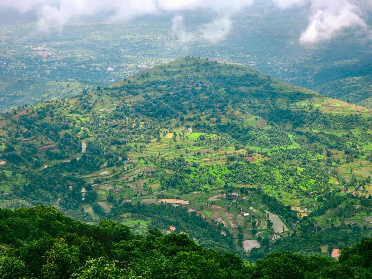 green mountains under cloudy skies with trees on the foreground