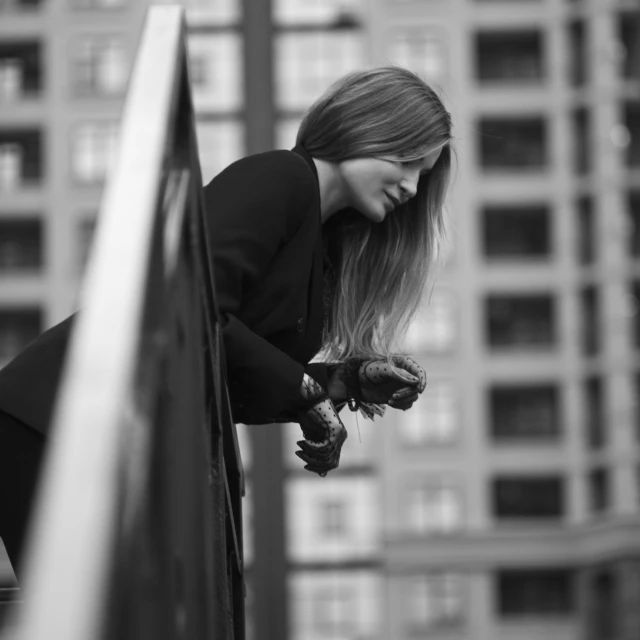 a lady leaning up against the ledge of a building