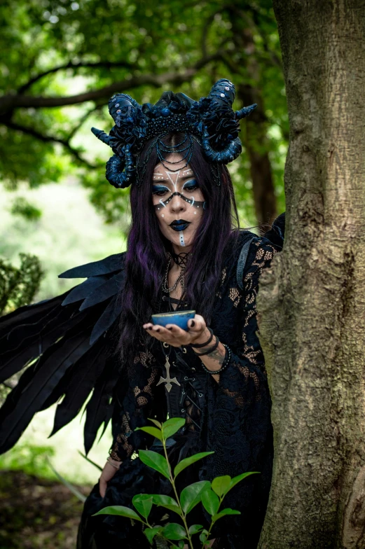 woman dressed up in dark colors with black and blue makeup using her phone