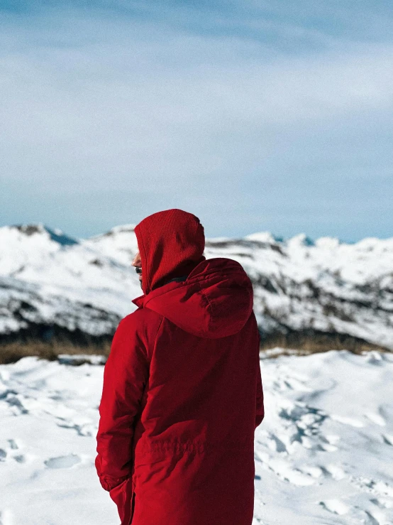 a person standing in the snow with mountains and sky in the background