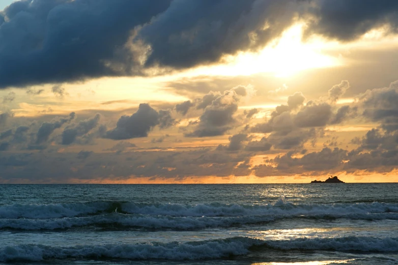 an ocean sunset with a ship in the distance