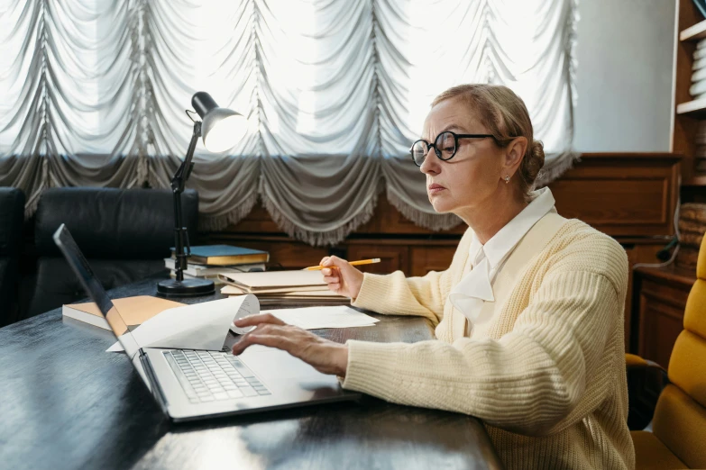 an old woman using her laptop computer at the desk