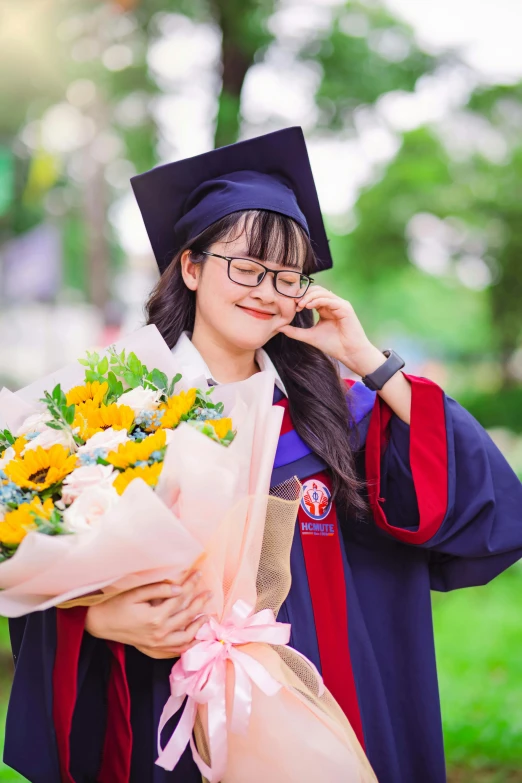 a young female student in her graduation robe with flowers on her arm