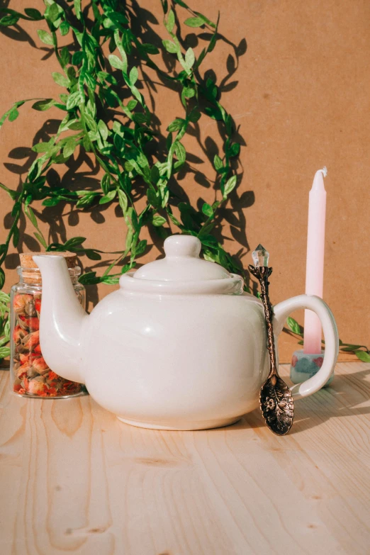 a white tea pot with a tea wand and tea glass