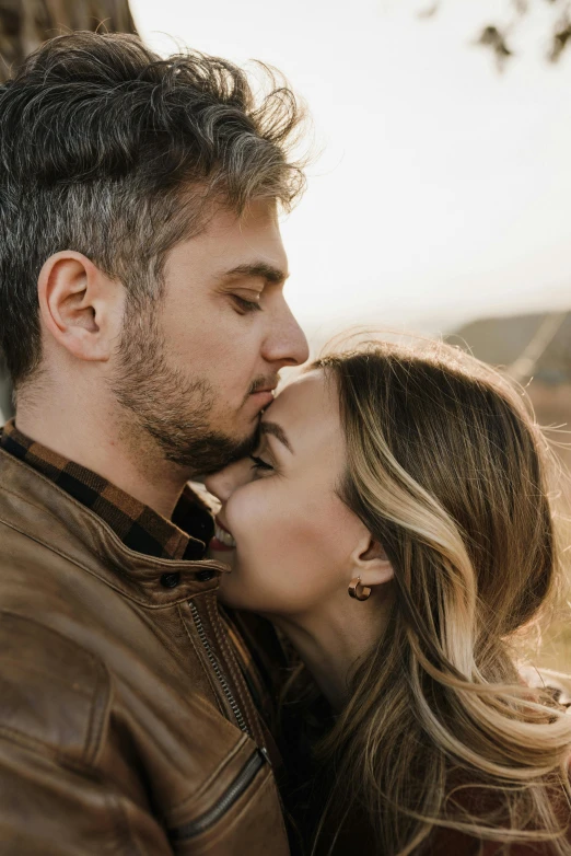 a man and a woman cuddling while standing close to each other