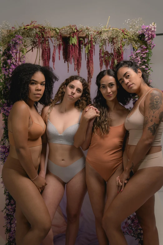 four women posing in their underwear in front of purple and purple floral wall