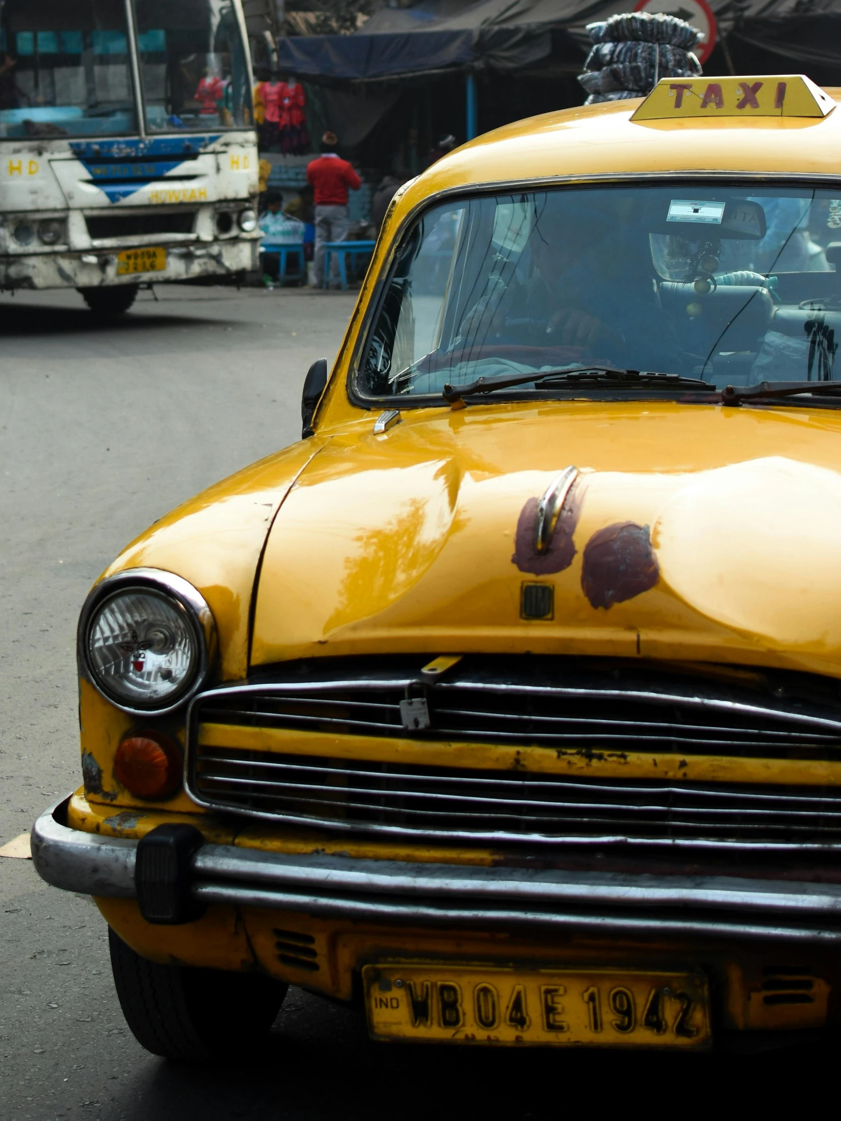 a taxi with large dentors driving in front of other cars