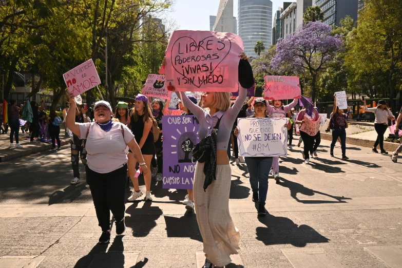 people holding protest signs and wearing headscarves in the street