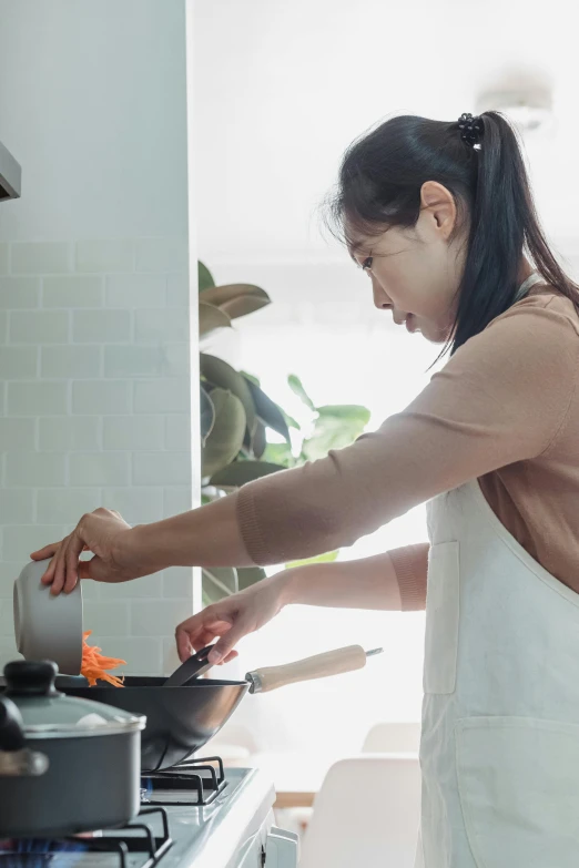 a woman in a kitchen is frying eggs on an electric range