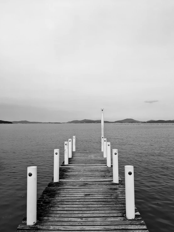 the water is calm and clear and the pier has two poles