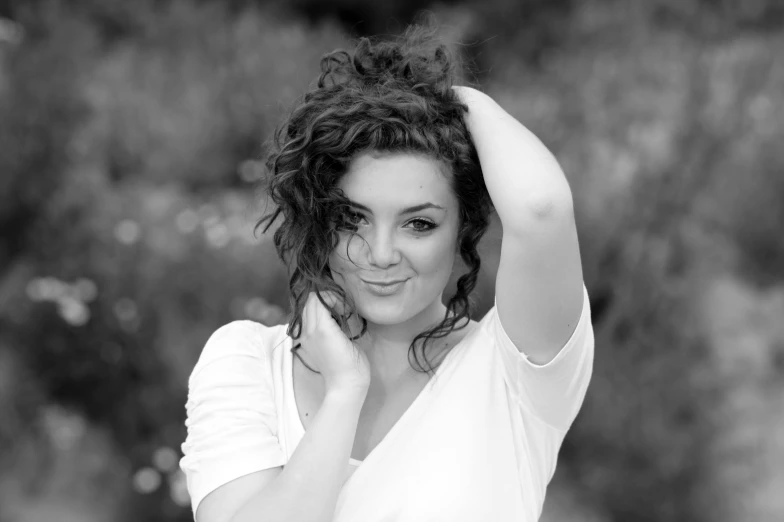 a black and white po of a woman with her hand on her hair