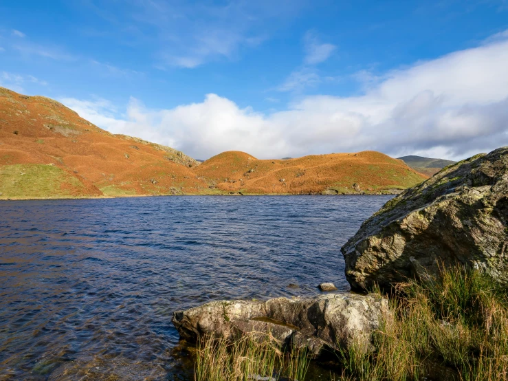 water and hills under blue sky with clouds