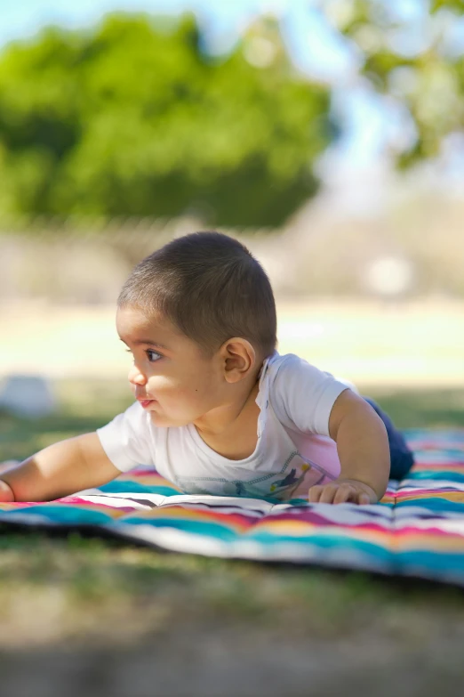 a baby laying on top of a blanket on the ground