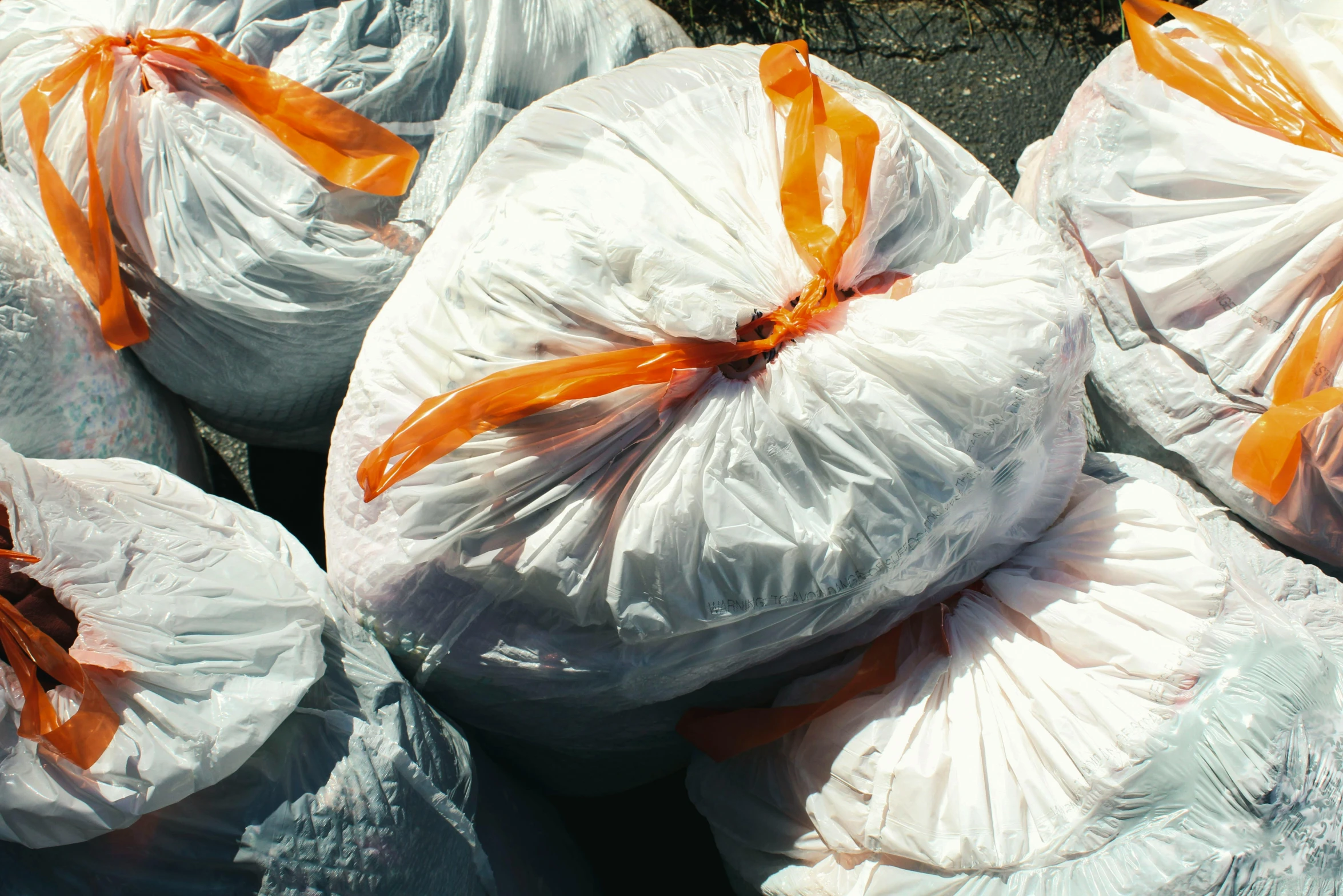 white bags covered with orange ribbon on a cement surface