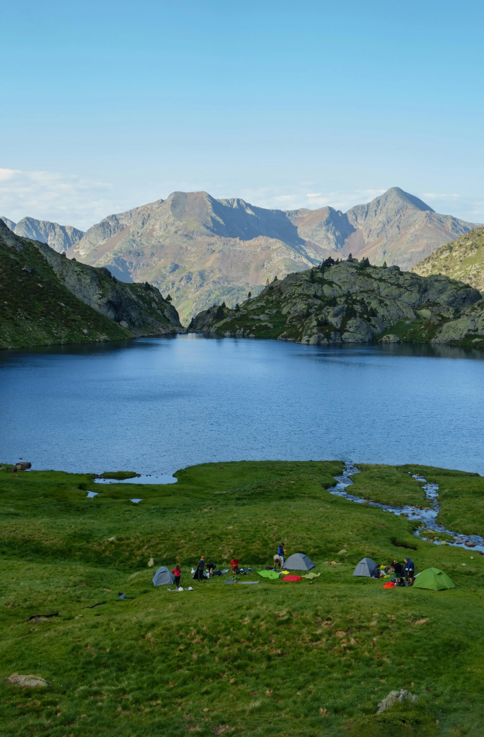 two tents are set up in the grass by a lake