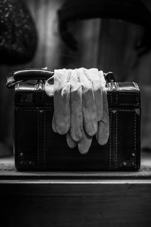 a pair of white gloves sitting on top of a briefcase