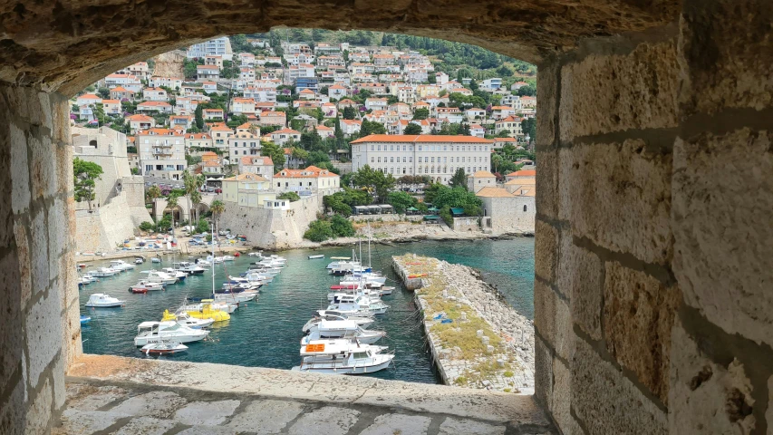 the view from a window in a stone building with boats on water