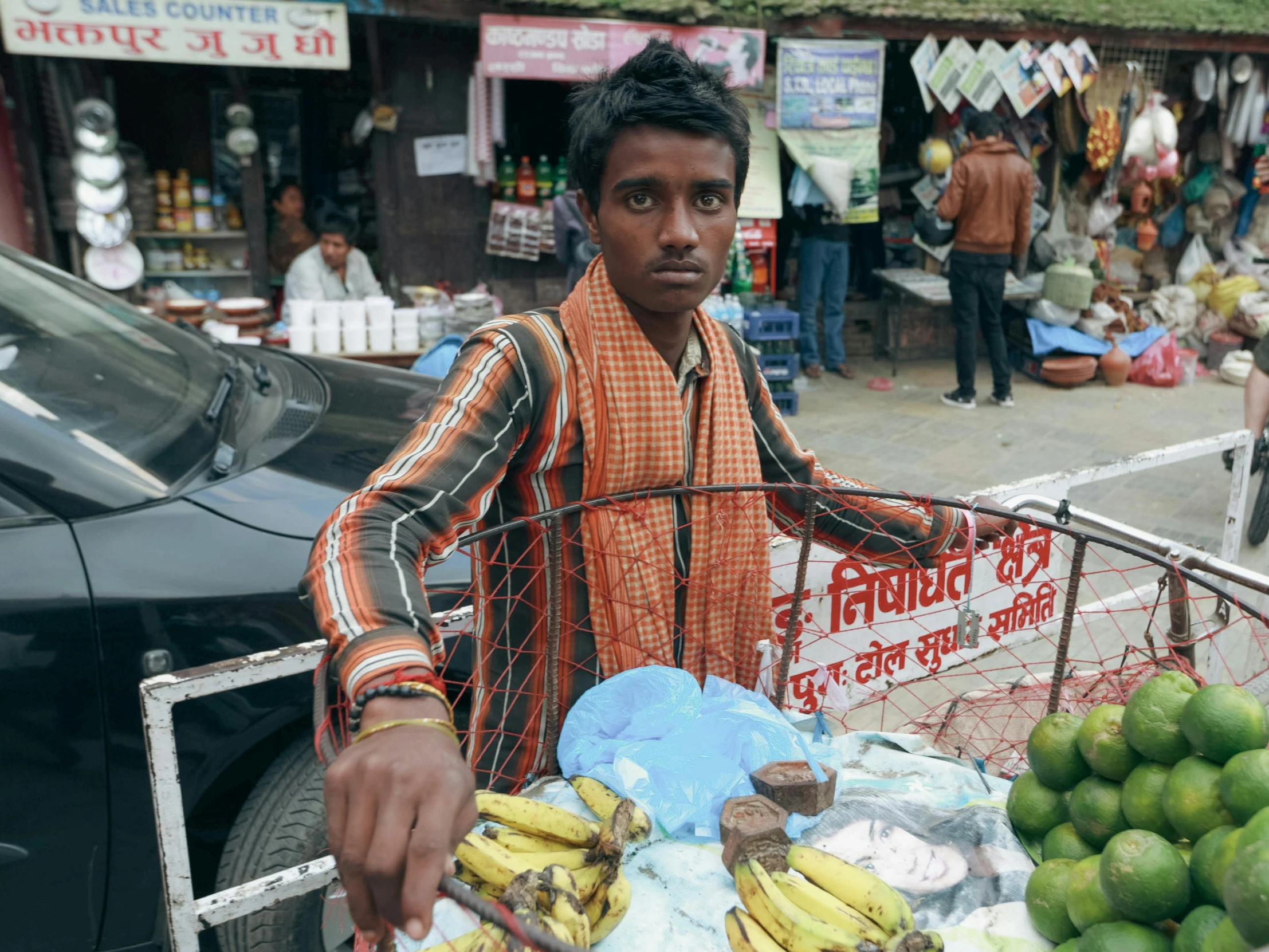 a man standing next to a cart full of bananas