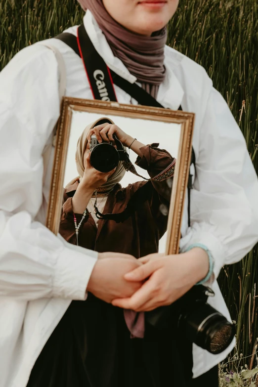 the woman in the scarf has a picture frame with the girl taking a picture