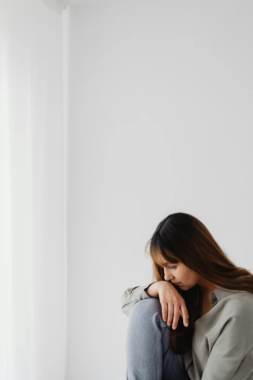 a woman wearing blue jeans sitting in an empty room