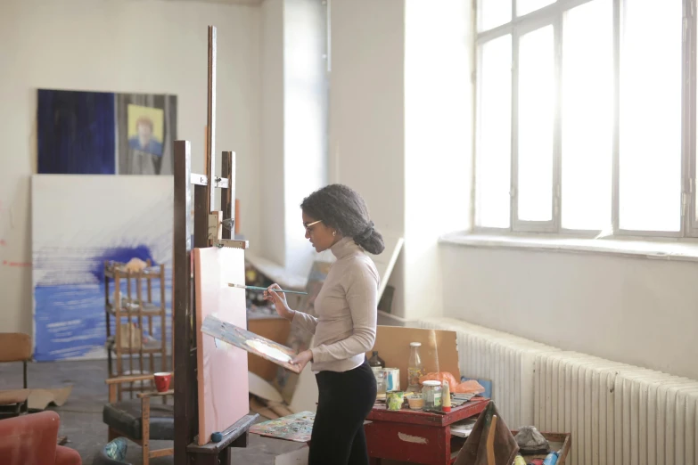 an african woman painting in her art room