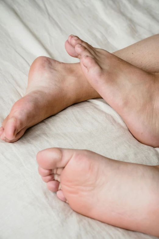 a man laying on top of a bed next to his bare toe