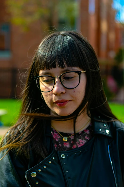 a girl with glasses standing in a park