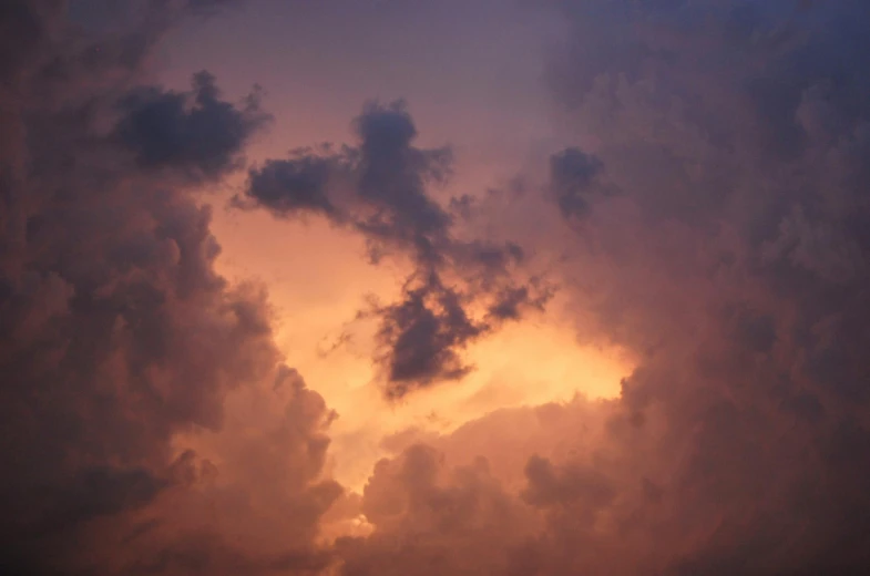 the sky is orange and white while clouds are dark blue