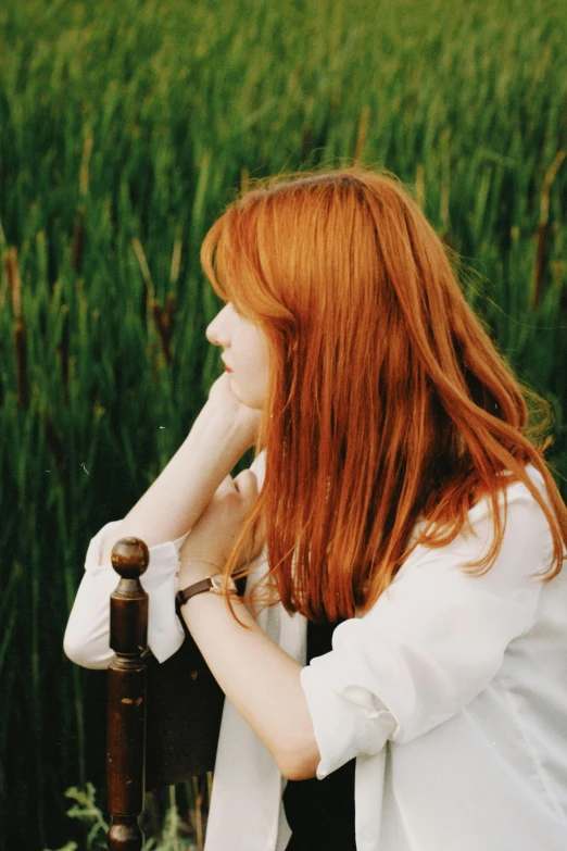 woman with red hair wearing white shirt standing by pole