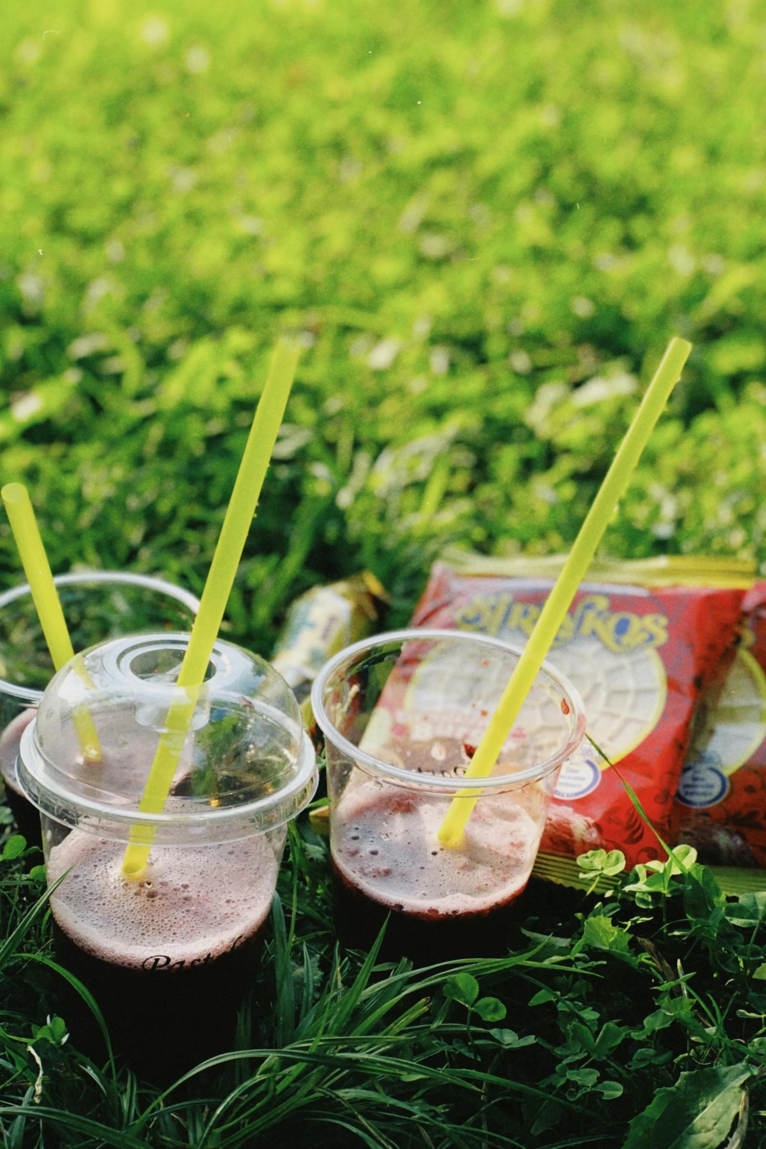 several beverages sitting on the grass in their plastic glasses