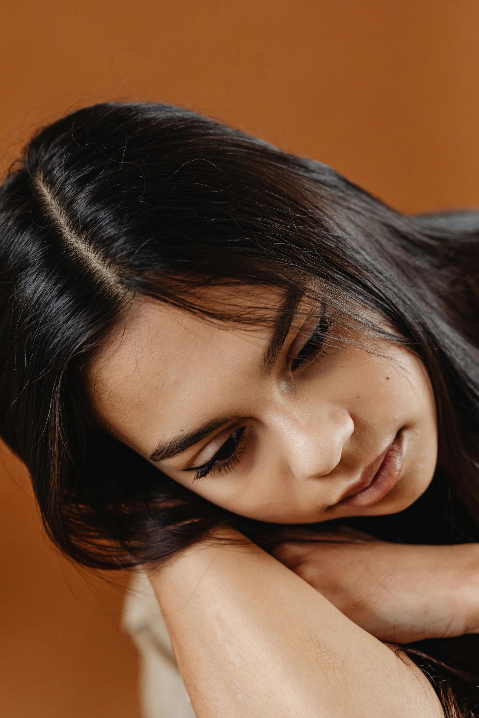 a woman sitting next to a wooden piece of furniture