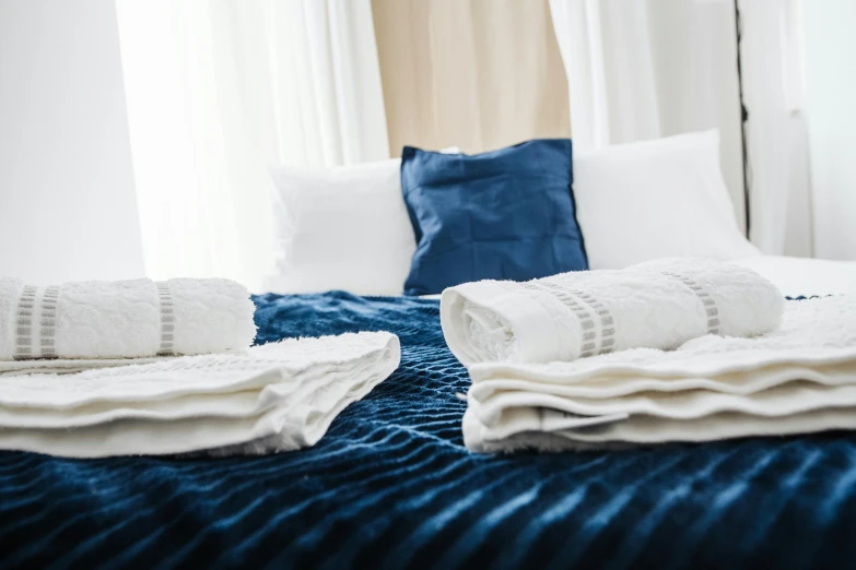 two folded towels sitting on top of a bed