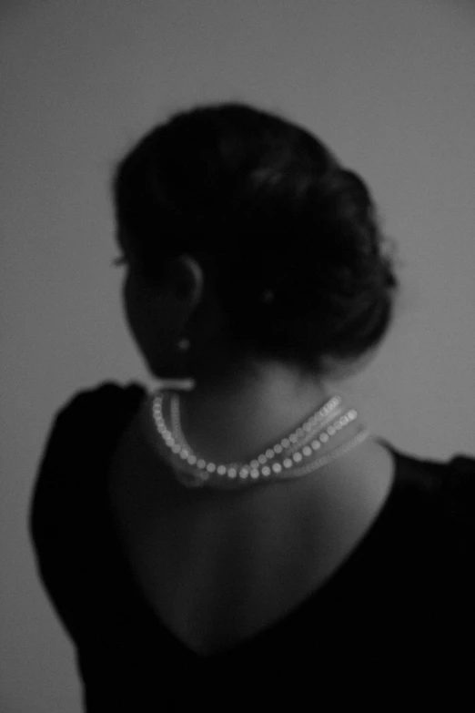 a woman with a pearls necklace is shown from behind