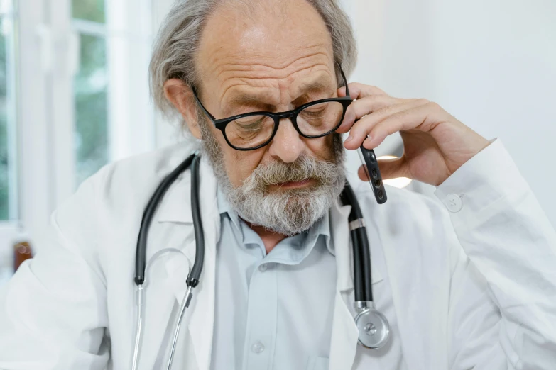 a graying man has glasses while he is sitting in front of a desk