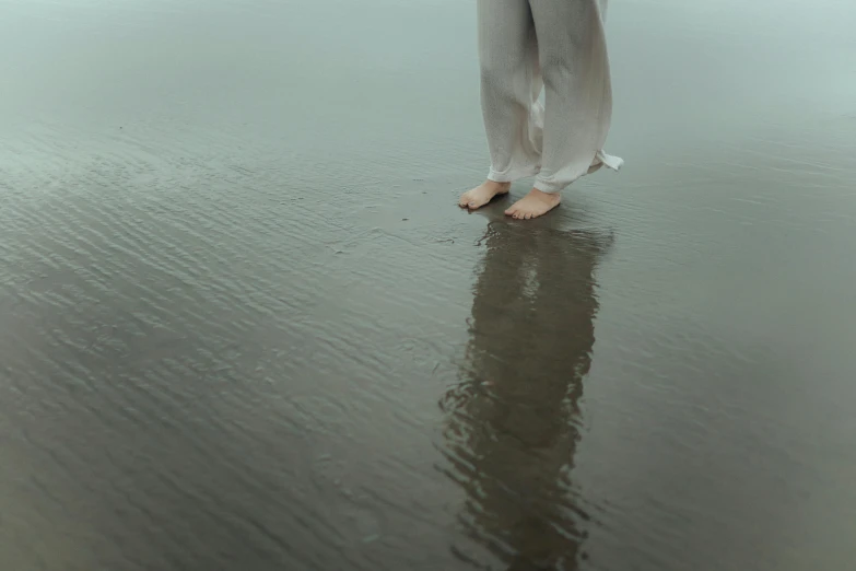 the view from behind the feet of a woman standing on sand