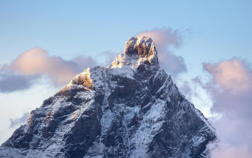 a snow covered mountain peak with clouds in the background