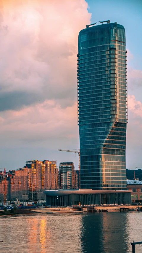 a large tall building near water under a cloudy sky