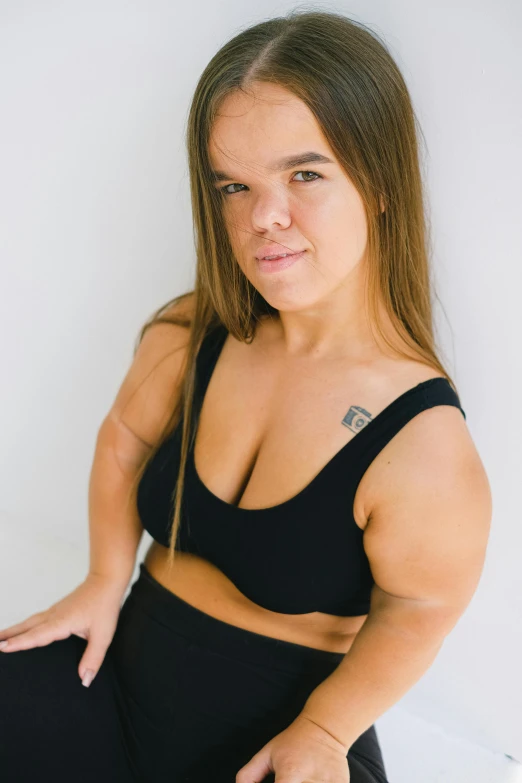 a woman in black tank top and black sweatpants with her arms crossed