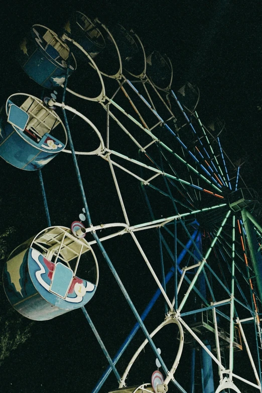 an old ferris wheel at night, including lights and rides