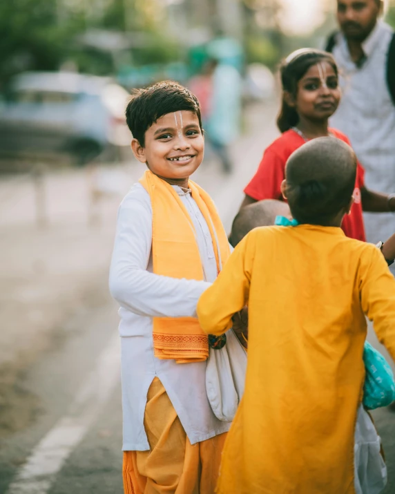 a small boy in yellow and orange looking at someone