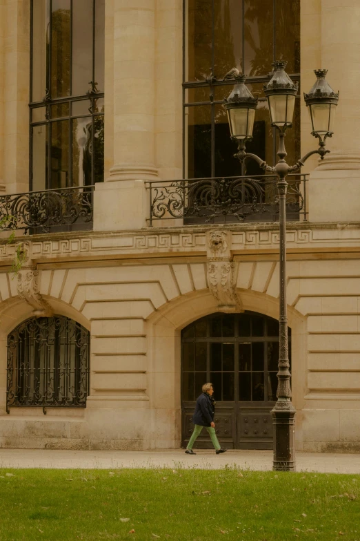 a man walking past a tall building next to a lamp post