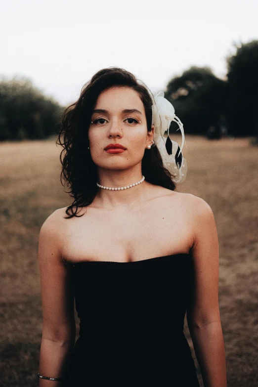 a woman in a black dress is holding a headpiece