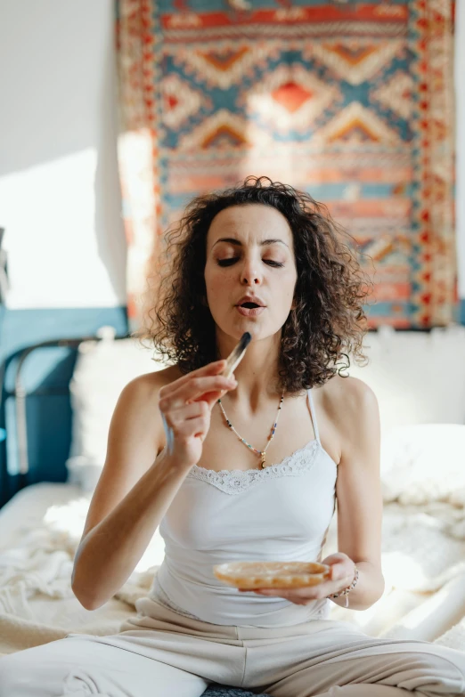 a woman holding an object while sitting on a bed