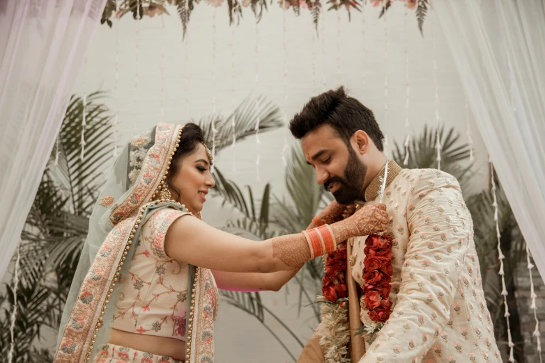 a man putting on a brides red and white saree