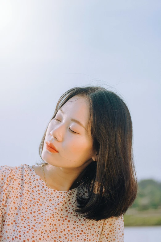 a woman sitting by the water and sun shining down