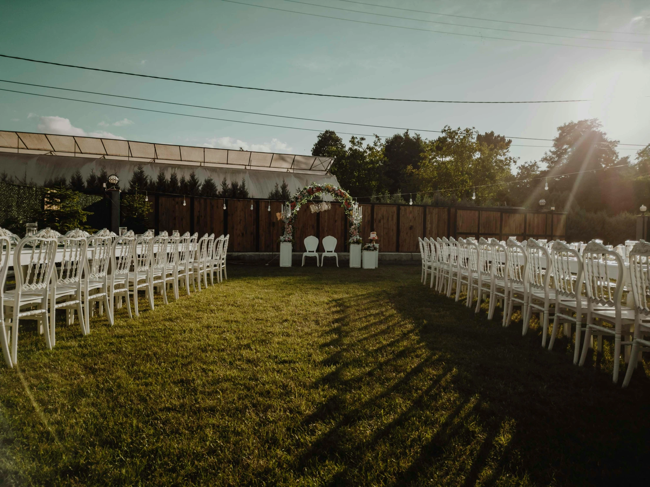 a set of white chairs next to a grassy field