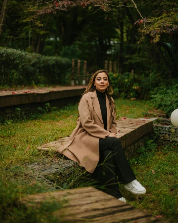 a woman is sitting on a wooden bench in the grass