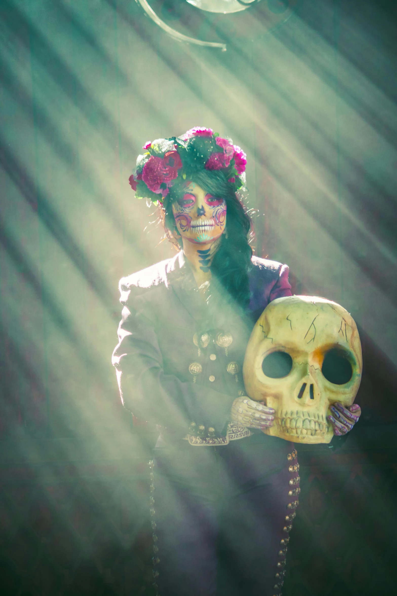 woman in mexican style makeup and skull holding up a carved skull