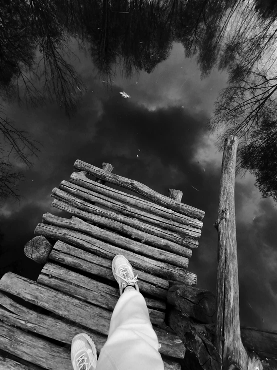 person sitting on a boardwalk next to a body of water