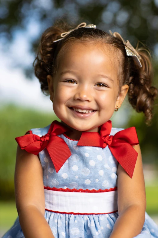 a little girl is smiling in her blue dress